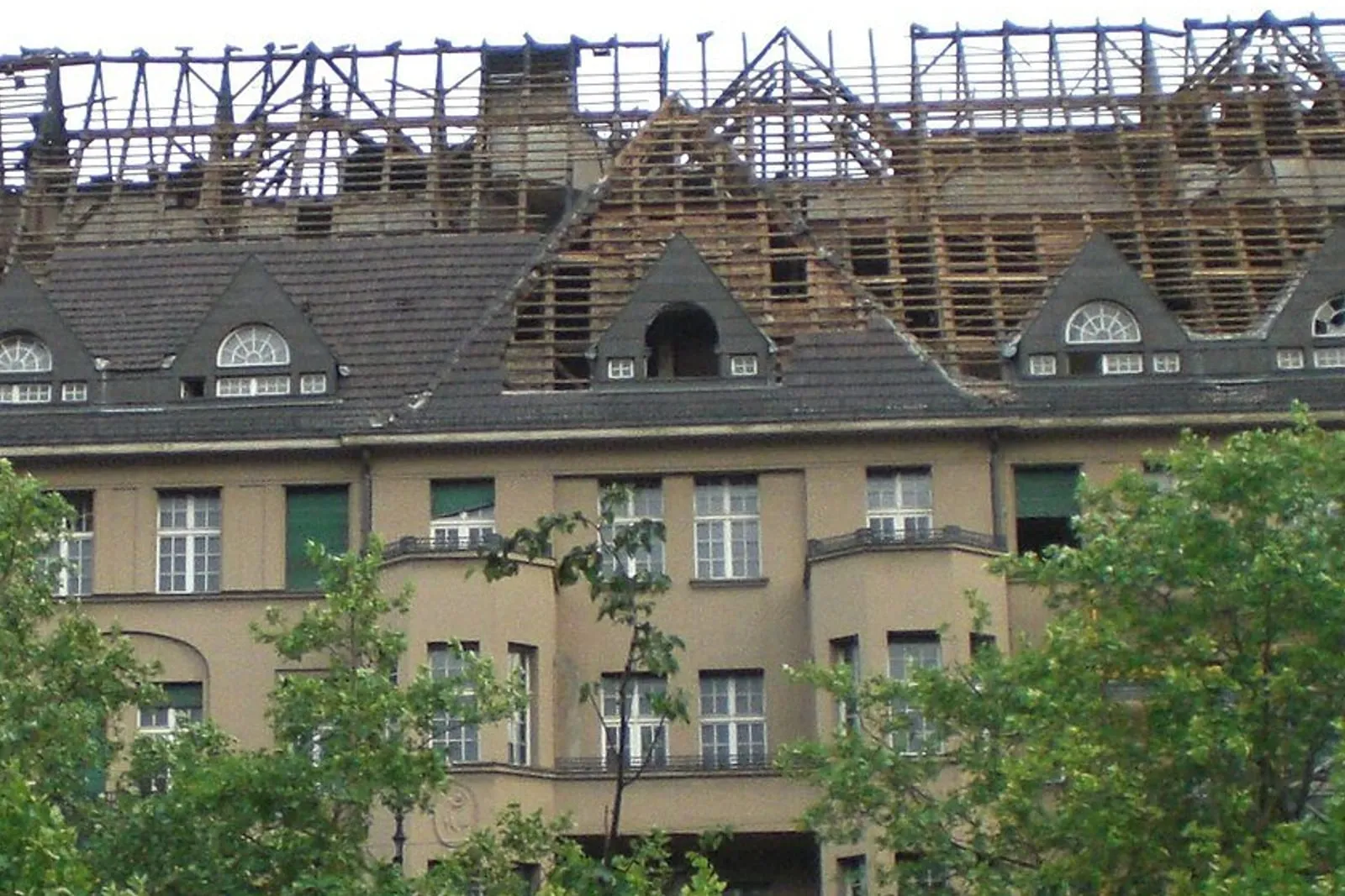 Mansard roof of an occupied apartment block taken back to the timber frame, the storeys below still in use.