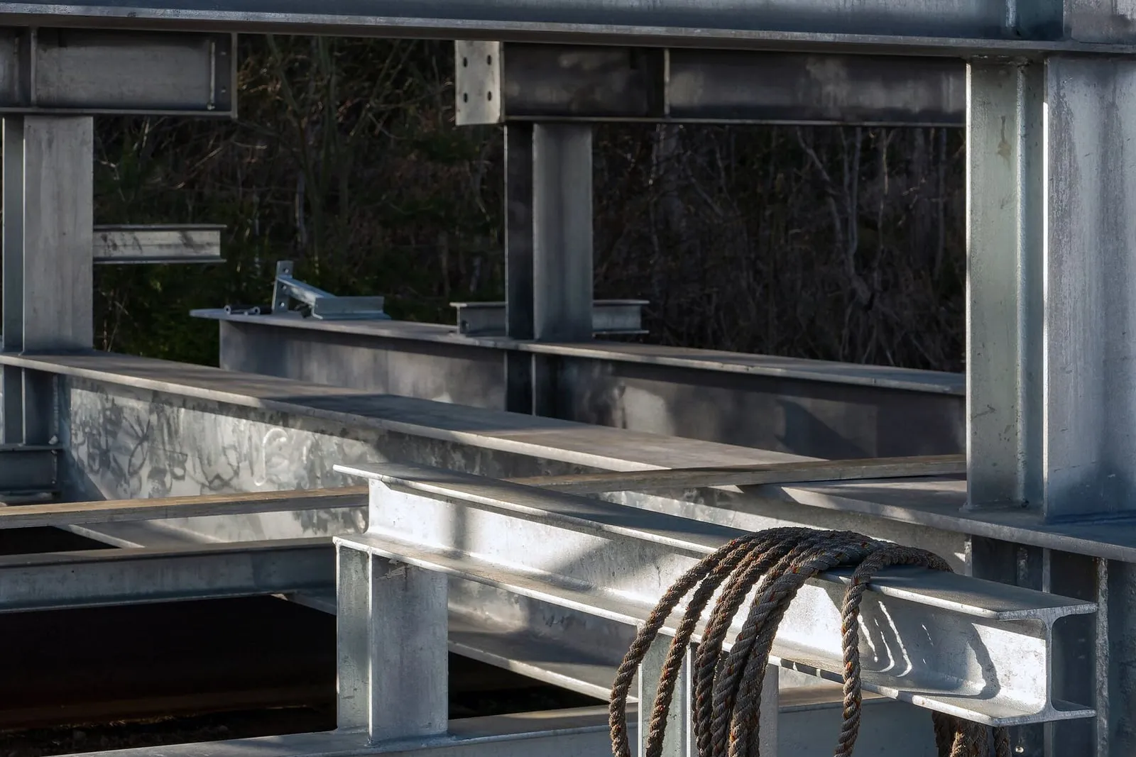 Steel beams set in place over a new support structure, a coil of reinforcing bar resting across them.