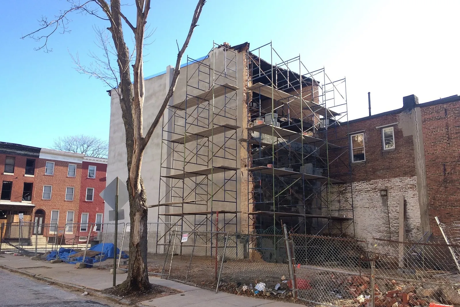 Scaffolding erected the full height of a brick row building while the exterior wall is worked on.