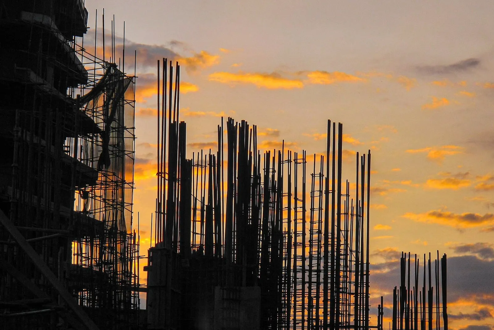 Reinforcing steel standing proud of concrete columns on a building frame under construction at dusk.